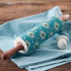 a rolling pin with flowers on it sitting on top of a blue napkin next to two white balls