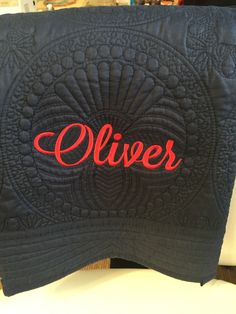 a close up of a black quilt with the word aliver written in red on it