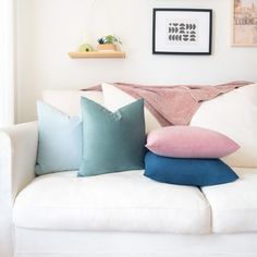 pillows are stacked on the back of a white couch