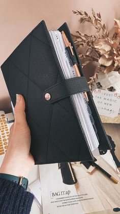 a person holding a black leather notebook in their hand