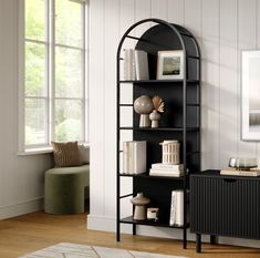 a black book shelf with books on it in a living room next to a window