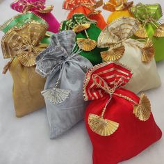 six bags with gold, silver, red and green decorations on them sitting on a white surface