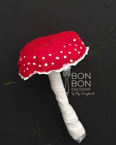 a red and white mushroom sitting on top of a black surface