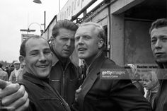 three men taking a selfie in front of a building with people standing around them