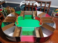 there is a cardboard model of a stadium on top of a table with chairs around it