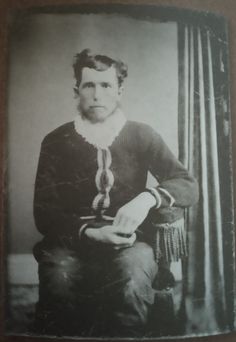 an old black and white photo of a woman sitting in a chair with her hand on her knee