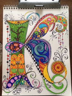 a drawing on paper with an abstract design and colorful swirly shapes, including the letter k