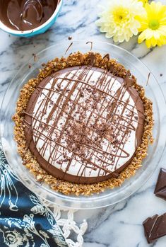 a pie with chocolate and whipped cream on top, sitting on a marble countertop