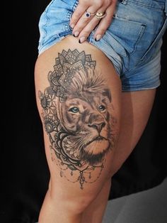 a woman's thigh with a lion tattoo on the leg and an ornate frame around it