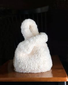 a white stuffed animal sitting on top of a wooden table