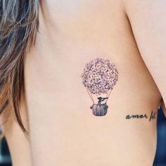 a woman with a tattoo on her stomach holding a hot air balloon in the shape of a flower