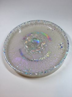 a clear glass plate with an iridescent design on the bottom and words written in white