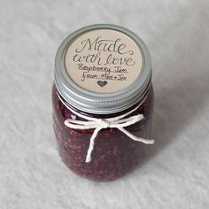 a jar filled with jam sitting on top of a white cloth covered floor next to a wooden spoon