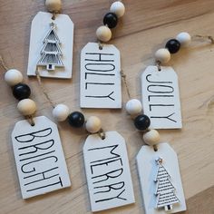 four tags with words and a christmas tree hanging from them on a wooden table top