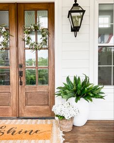 the front door is decorated with wreaths and potted plants