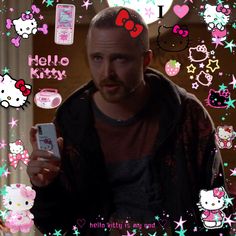 a man holding a cell phone with hello kitty stickers all over the wall behind him