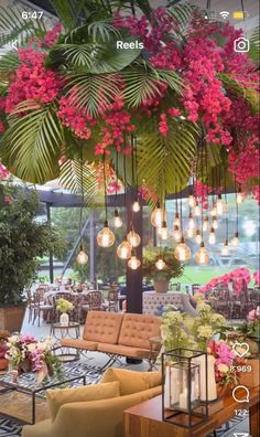 a living room filled with lots of furniture and flowers hanging from the ceiling above it