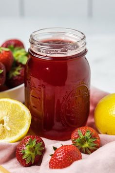 some strawberries and lemons are on a towel next to a jar of jam