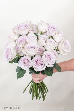 a woman holding a bouquet of white and pink roses