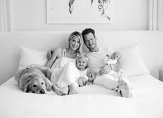 a man, woman and baby are laying on a bed with a dog in front of them