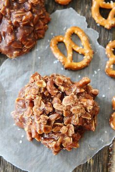 some pretzels and cookies are on a piece of wax paper next to them