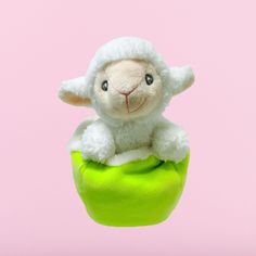 a stuffed sheep sitting on top of a green ball in the air with it's eyes open