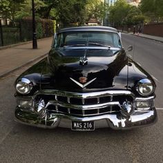 an old black car is parked on the street