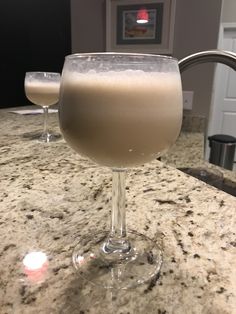 two glasses filled with liquid sitting on top of a counter