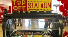 a display case filled with lots of different types of pastries in front of a sign that says top off station