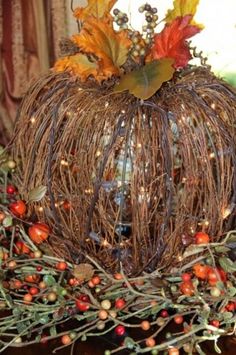 a decorative pumpkin with leaves and berries on it's head sitting on a table