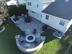 an aerial view of a patio and fire pit in the back yard with chairs around it