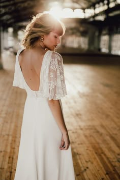 a woman in a white dress standing on a wooden floor with her back to the camera