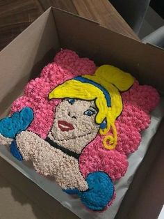 there is a cake in the box that looks like a woman with blonde hair and blue gloves