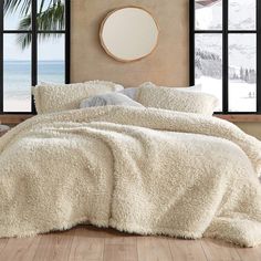 a bed with white fluffy blankets and pillows