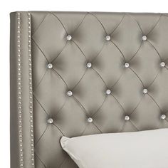 an upholstered headboard with white pillows and beaded trimmings on it