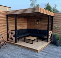 an outdoor living area with black furniture and wood siding on the walls, covered in wooden slats