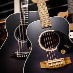 two black acoustic guitars sitting side by side