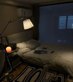 a bedroom with a bed, desk and lamp in it's corner next to a window