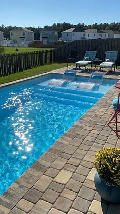 an empty swimming pool surrounded by lawn chairs and flowers on the side of the pool