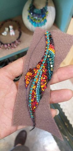 a hand holding a piece of cloth with beads on it