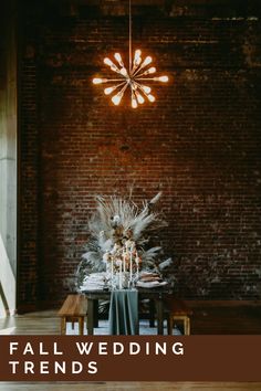 a dining room table set up with candles and flowers on it, surrounded by brick walls