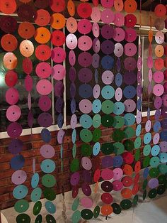 a room filled with lots of different colored circles hanging from the ceiling next to a window