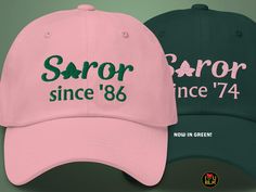 two baseball caps with the same color and font on each cap, one in green and one in pink