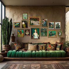 a living room filled with green couches and pictures on the wall next to potted plants