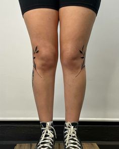 the legs and ankles of a woman with tattoos on her leg, standing on a wooden platform