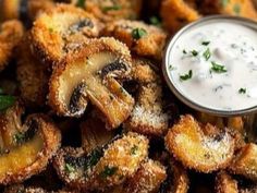 some fried food is sitting on a plate with a small bowl of ranch dressing next to it