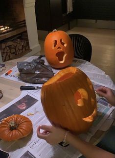 two pumpkins sitting on top of a table next to each other with faces carved into them