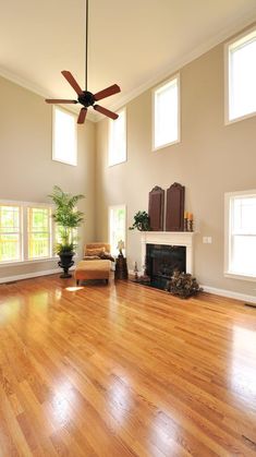 an empty living room with wood floors and ceiling fan in the middle of the room