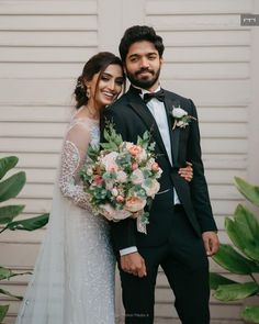 a bride and groom standing next to each other in front of a white garage door