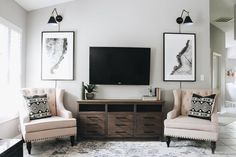 a living room with two chairs and a television mounted on the wall in front of it